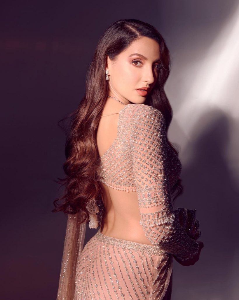 नोरा फतेही ने इस लुक में बेबी पिंक रंग की साड़ी पहनी है और बालो को खुले रखे है जिसमें नोरा काफी हॉट लग रही है लुक को कम्पलीट करने के लिए नोरा ने डायमंड जवेलरी और लाइट मेकअप का उस किया है।