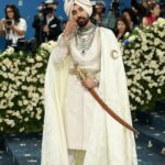 मेट गाला में इतिहास रचने वाले गायक दिलजीत दोसांझ ने डिजाइनर प्रबल गुरुंग द्वारा तैयार किया गया कस्टम व्हाइट लुक पहना था। उनके आउटफिट में महाराजा भूपिंदर सिंह से प्रेरित पंखों वाली पगड़ी और कई हीरे के हार थे। उन्होंने अपने पहनावे के हिस्से के रूप में एक शेर के सिर वाली तलवार (किरपान) भी पहनी थी। (Photo Credit: Instagram/@diljitdosanjh)