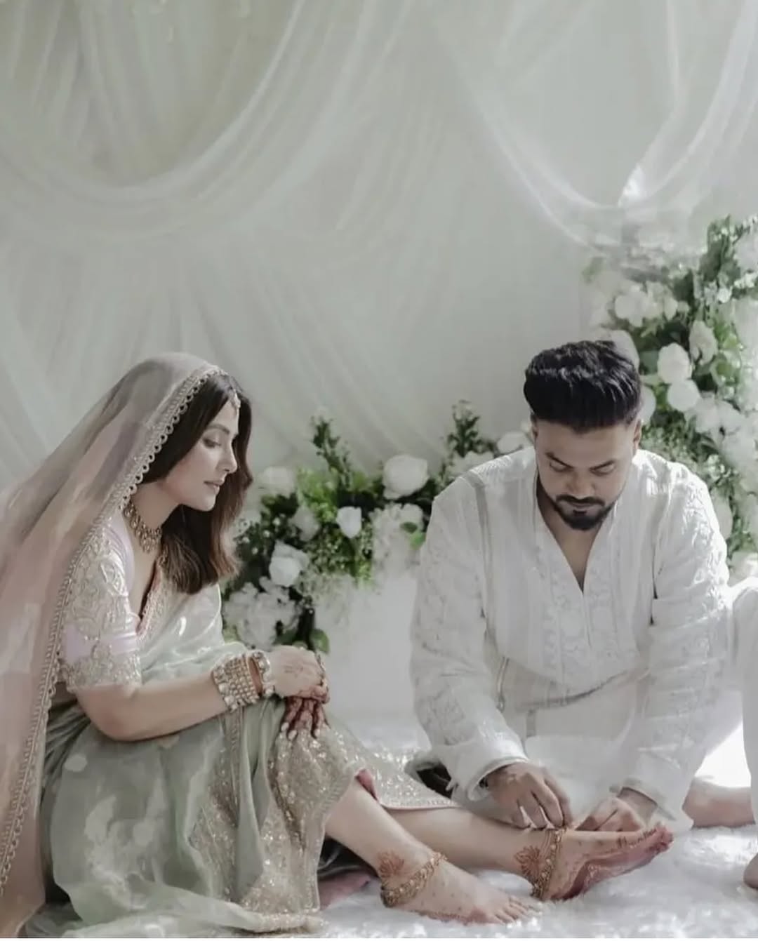 हिना ने अपनी शादी में खूबसूरत ओपल ग्रीन रंग का हैंडलूम साड़ी पहना। इस साड़ी की बुनाई में सोने और चांदी के धागों से सदियों पुराने पारंपरिक मोटिफ्स को खूबसूरती से उकेरा गया था। वहीं दूल्हें बने रॉकी ने मनीष मल्‍होत्रा का सिग्नेचर एक्रू कुर्ता ही पहना है। Image Credit: viralbhayani Instagram