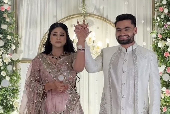 सफेद शेरवानी में रिंकू और हल्के गुलाबी लहंगे में प्रिया सरोज एक-दूसरे का हाथ थामे स्टेज तक पहुंचे और विधि-विधान से रिंग सेरेमनी की रस्म को पूरा किया। Image Credit: X Handle